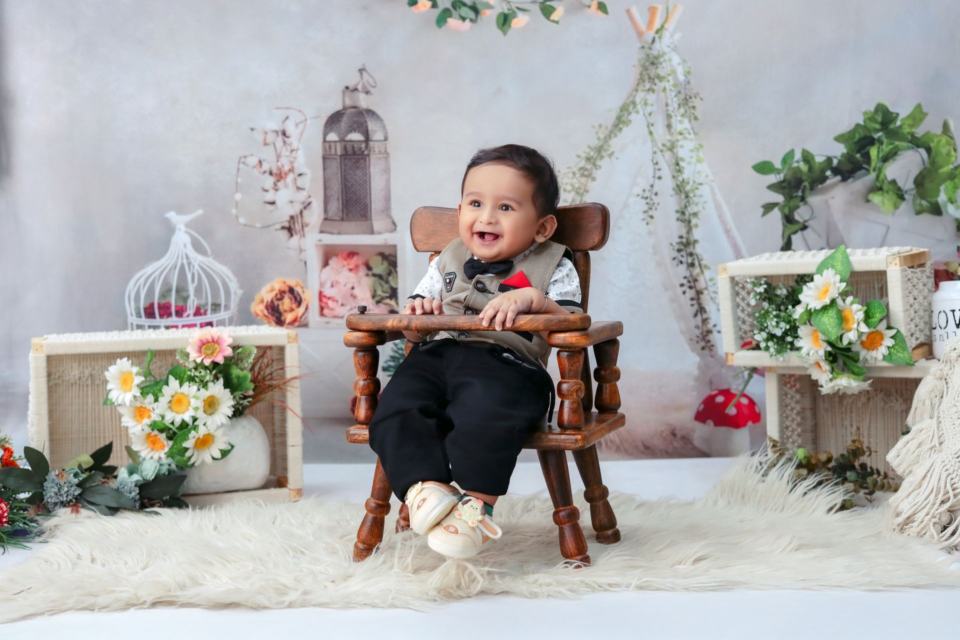 Adorable baby sitting in a wooden chair surrounded by floral decor, smiling indoors.