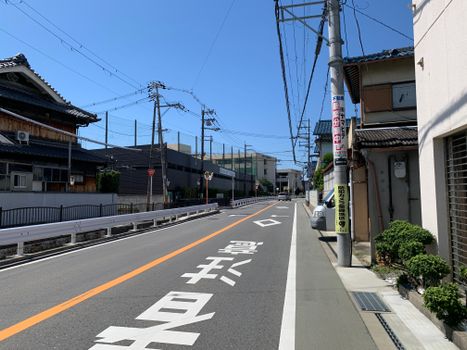 Empty suburban street in Japan with traditional houses and blue sky.