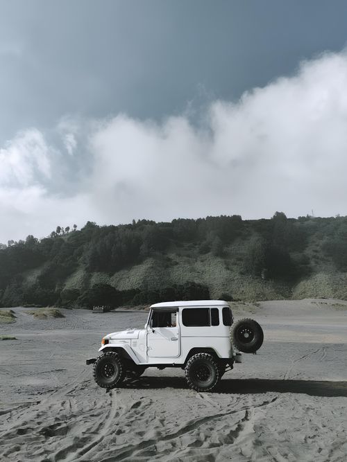 Free Explore the rugged terrain of East Java with this classic vintage 4x4 vehicle on sandy dunes. Stock Photo