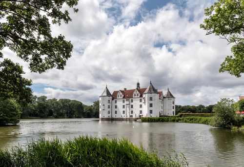 Free Explore the historic beauty of Glücksburg Castle reflecting in a serene lake under a vibrant sky. Stock Photo