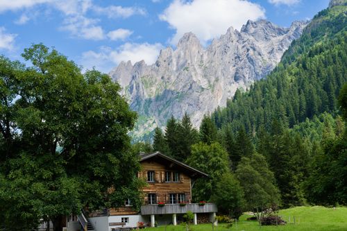 Free A picturesque Swiss chalet set against dramatic alpine mountains and lush forests. Stock Photo