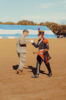 Two military officers in formal attire exchange greetings on a ceremonial field.