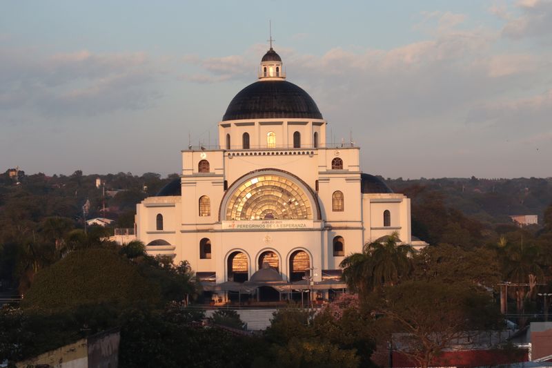 The domed Basilica of Our Lady of Caacupé in Paraguay glowing in golden sunset light.