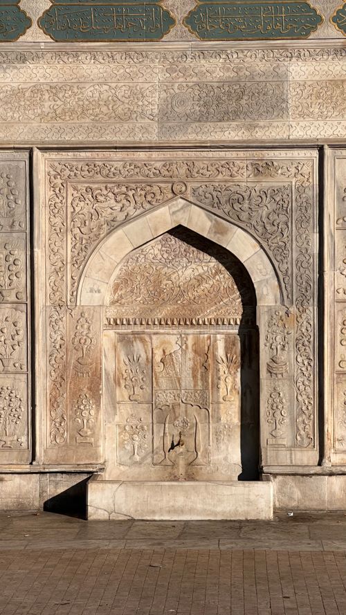 Free A beautifully detailed stone archway with intricate carvings and Arabic inscriptions. Stock Photo