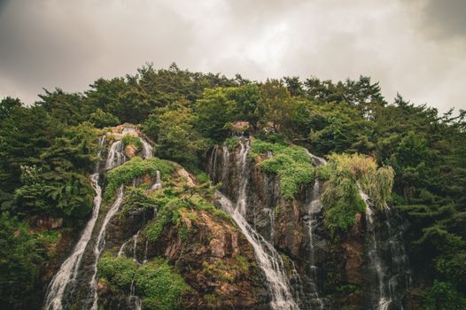 Stunning waterfall tumbles over lush, green cliffs amid a serene forest landscape in Seoul, South Korea.