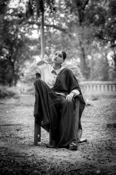 Black and white portrait of a woman in a saree sitting outdoors, embodying elegance.