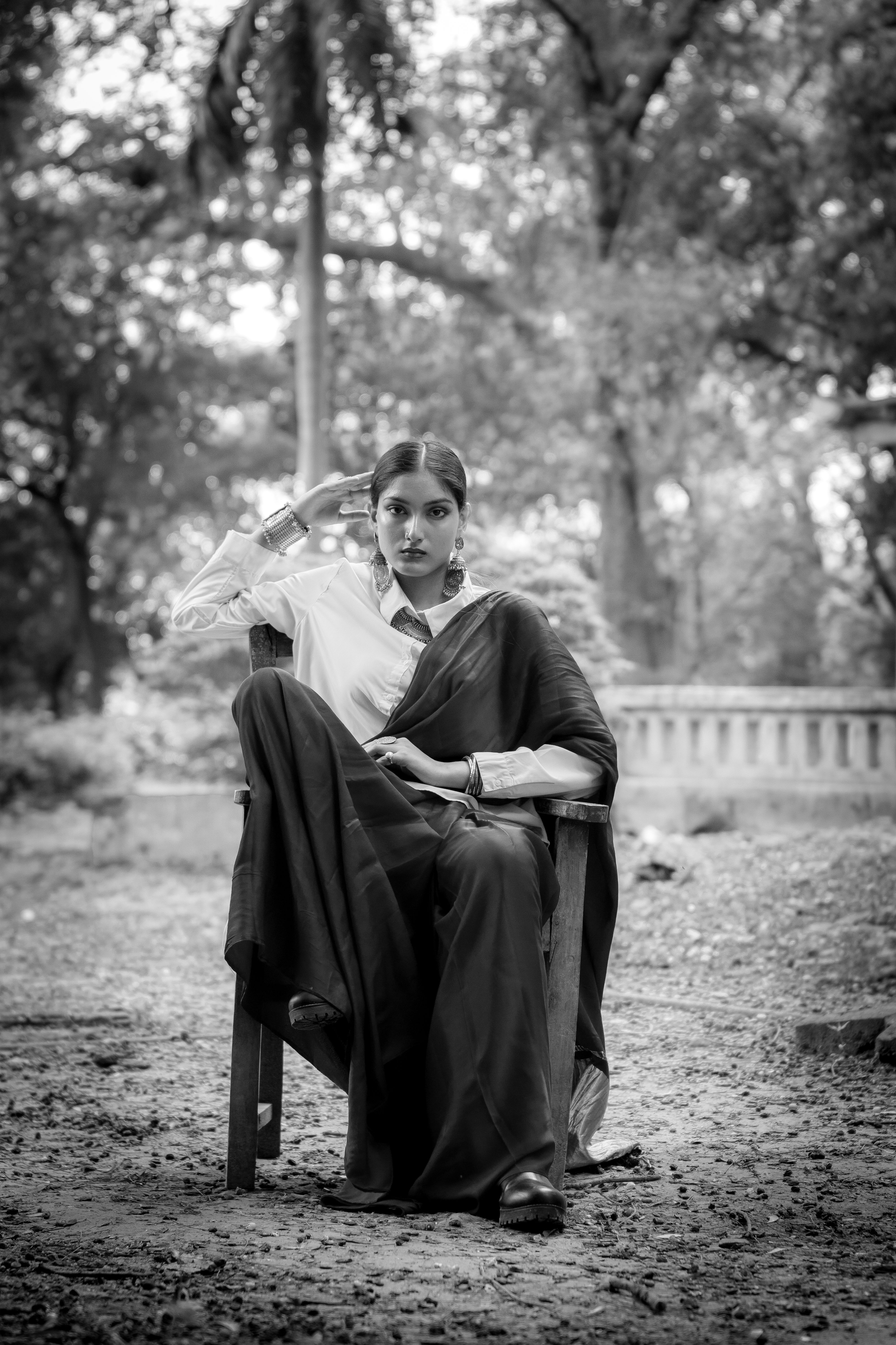 Black and white portrait of a woman in traditional saree with a serene outdoor backdrop.