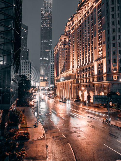 Free Dramatic city street at night with illuminated buildings and wet pavement showcasing urban life. Stock Photo