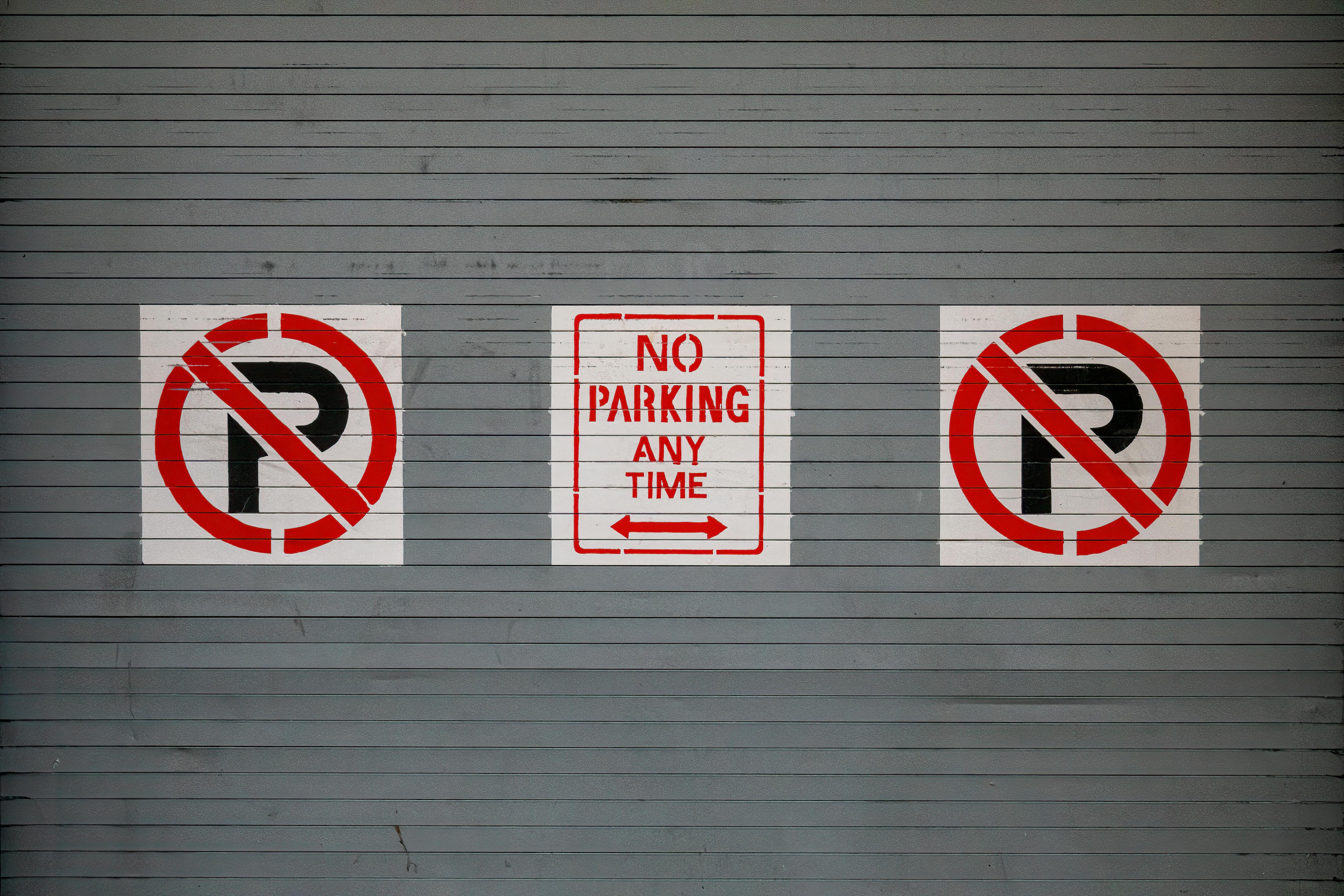 Red no parking signs on a gray wall in San Francisco, California.