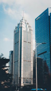 Tall modern skyscraper with reflective windows in a bustling city environment.