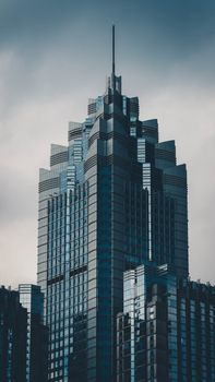 Dramatic view of a modern skyscraper with cloudy sky, showcasing urban architecture.
