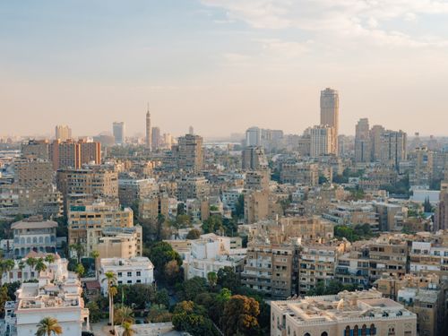 Free Aerial view of Cairo's urban skyline featuring prominent buildings and the Cairo Tower at dusk. Stock Photo