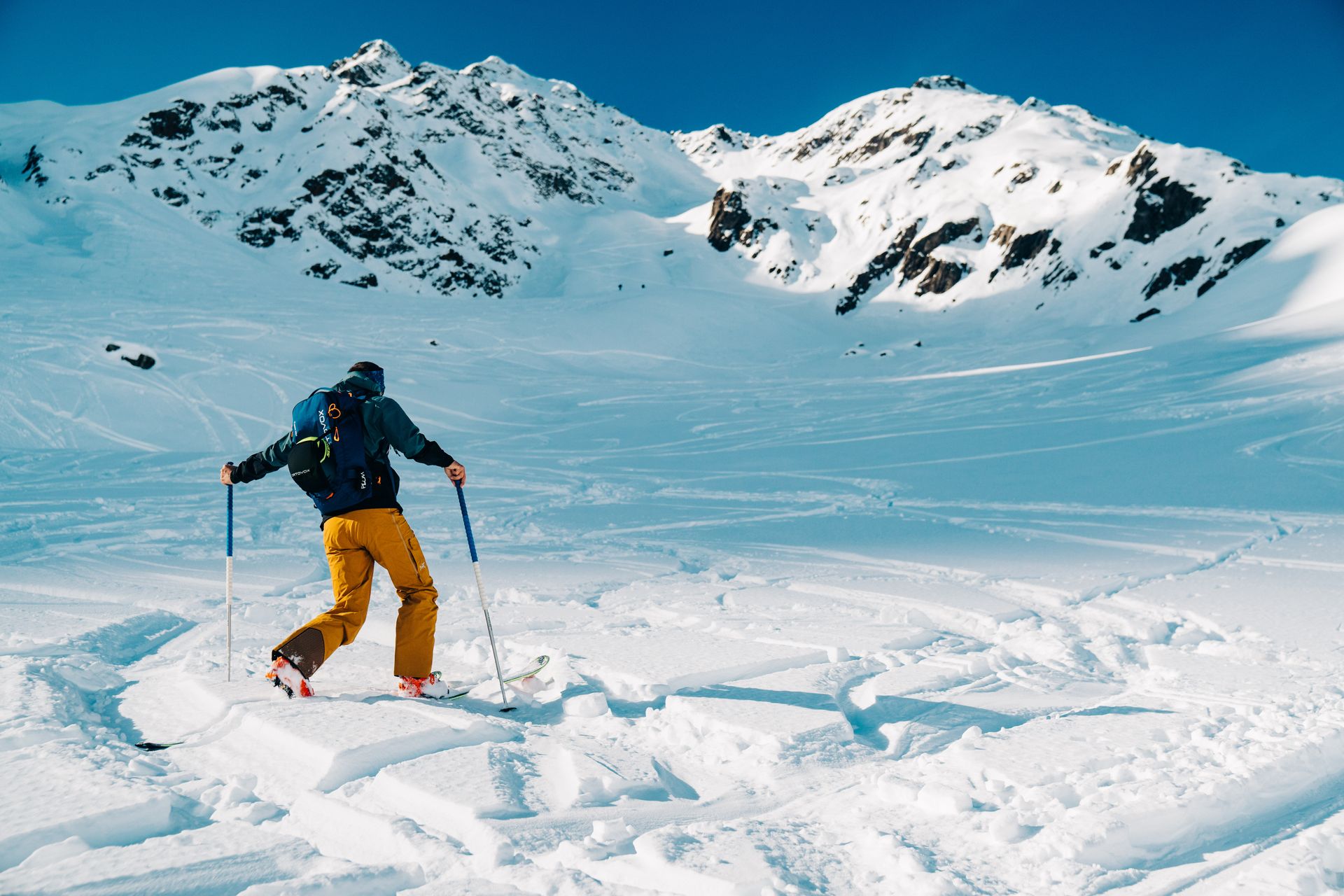 A skier navigates fresh snow in a picturesque mountain setting on a sunny day.
