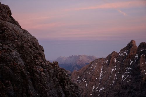 Free Dramatic mountain vista at dawn with soft pink skies and rugged peaks. Stock Photo
