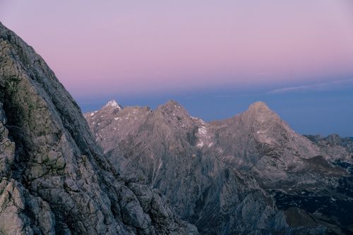 Free Majestic mountain range at dawn with a soft pink and blue sky, capturing serene natural beauty. Stock Photo