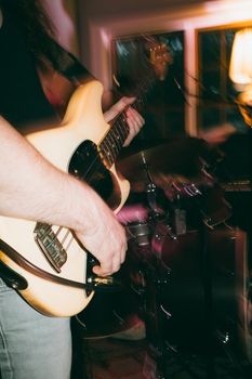 Blurred motion capture of a bassist playing electric guitar during a live indoor performance.