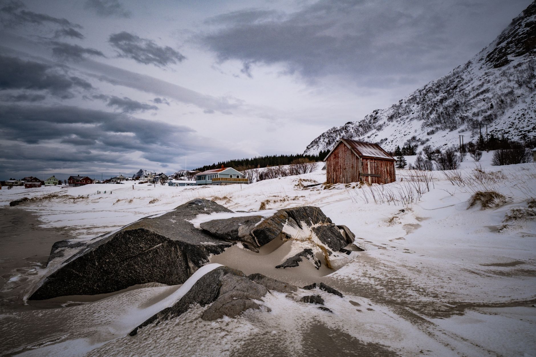 Serene winter scene featuring a historic cabin in a snowy Arctic landscape with cloudy skies.