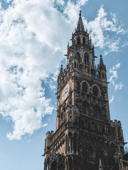 Capture of the historic Marienplatz Glockenspiel tower against a bright blue sky in Munich.