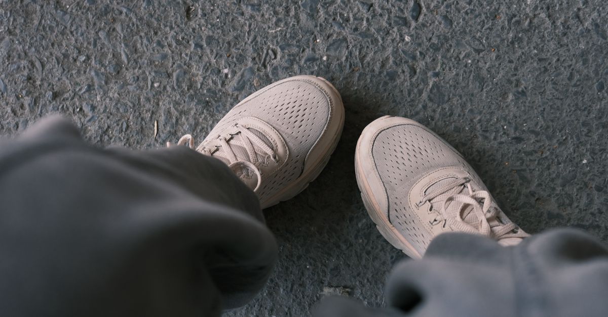 Casual white sneakers pictured on a textured pavement, perfect for lifestyle and fashion themes.