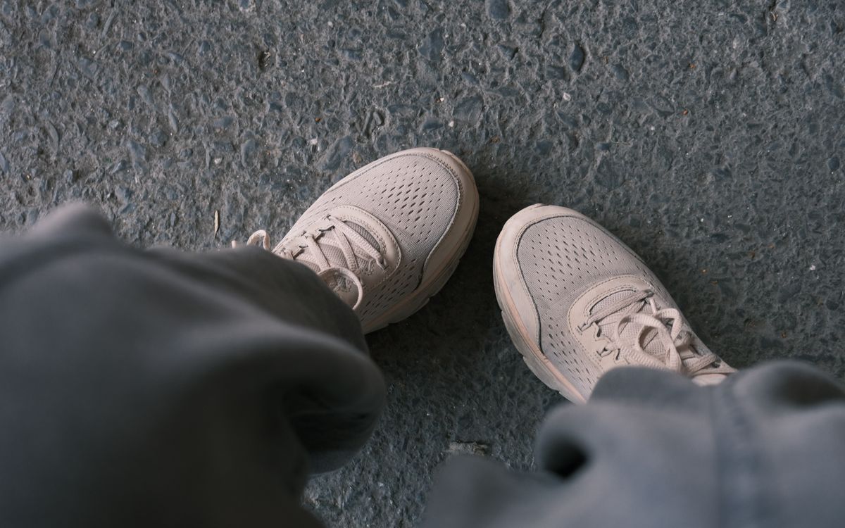 Casual white sneakers pictured on a textured pavement, perfect for lifestyle and fashion themes.