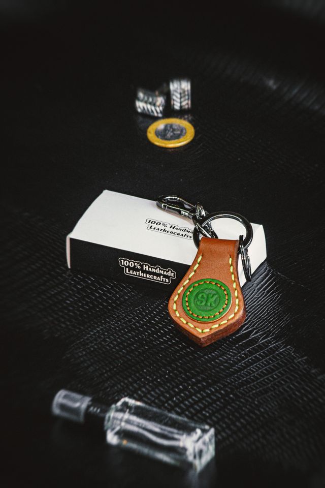 Hand-stitched leather keyring on a dark textured surface — photo by Atelier Kommpass on Pexels