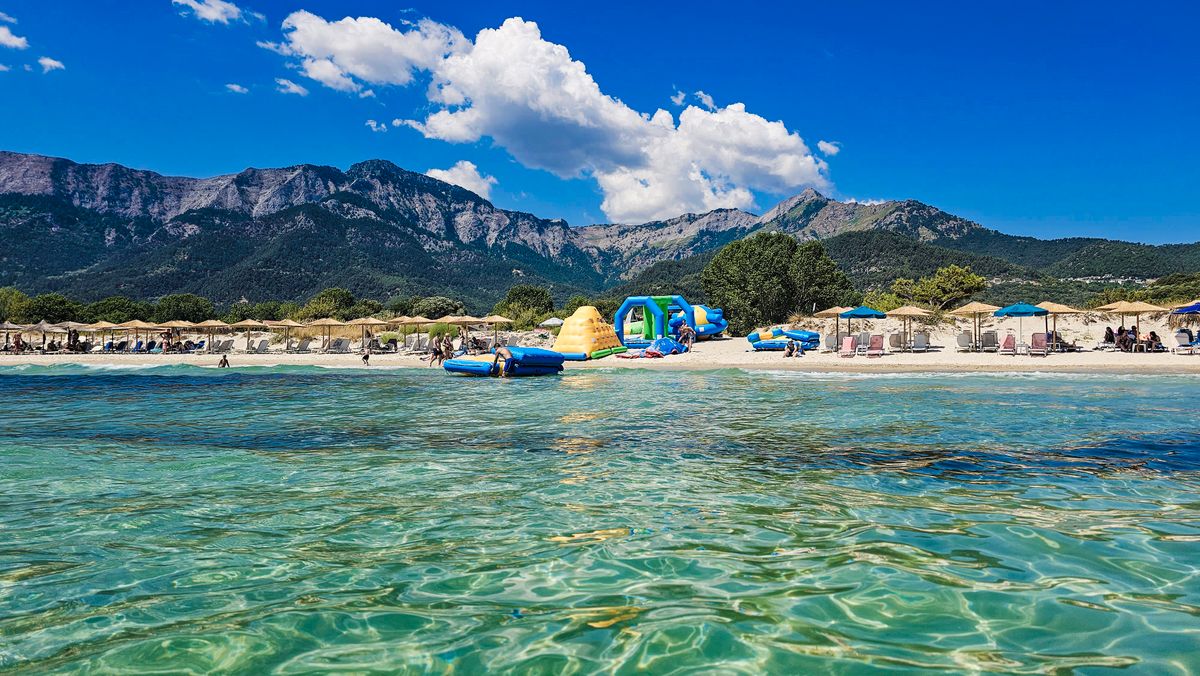 Plaja cu apa turcoaz si creasta muntoasa in fundal