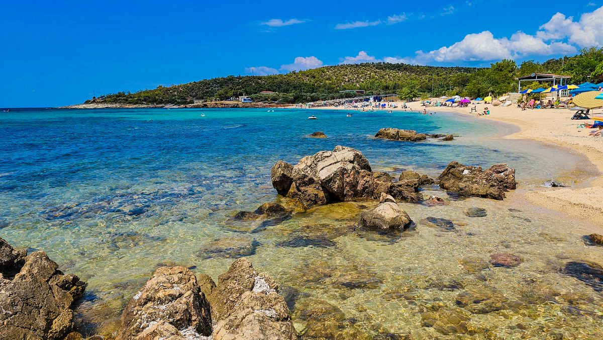 Plajă din Thassos cu apă cristalină și munții împăduriți ai insulei în fundal