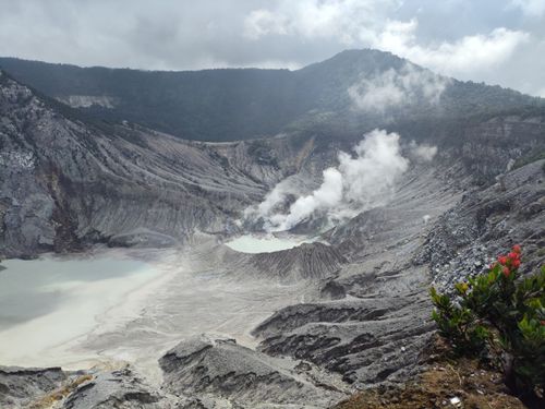 Free A stunning view of a steaming volcanic crater nestled in mountainous terrain. Stock Photo
