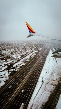 A snowy aerial view of a busy Chicago highway seen from an airplane window during winter.
