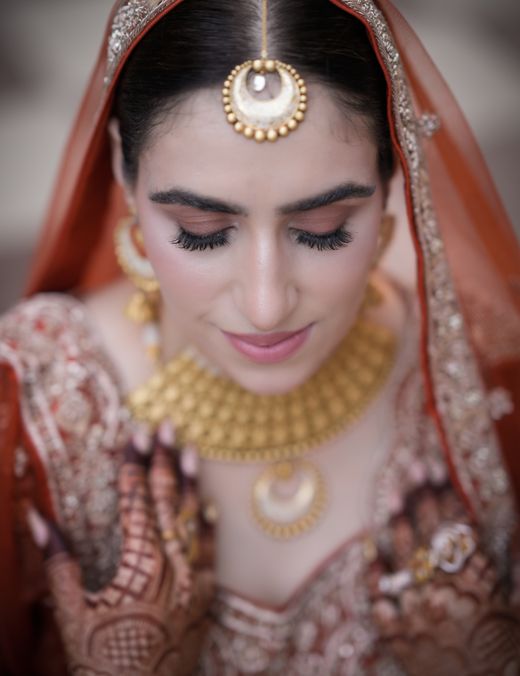 A bride wearing a gold choker and maang tikka
