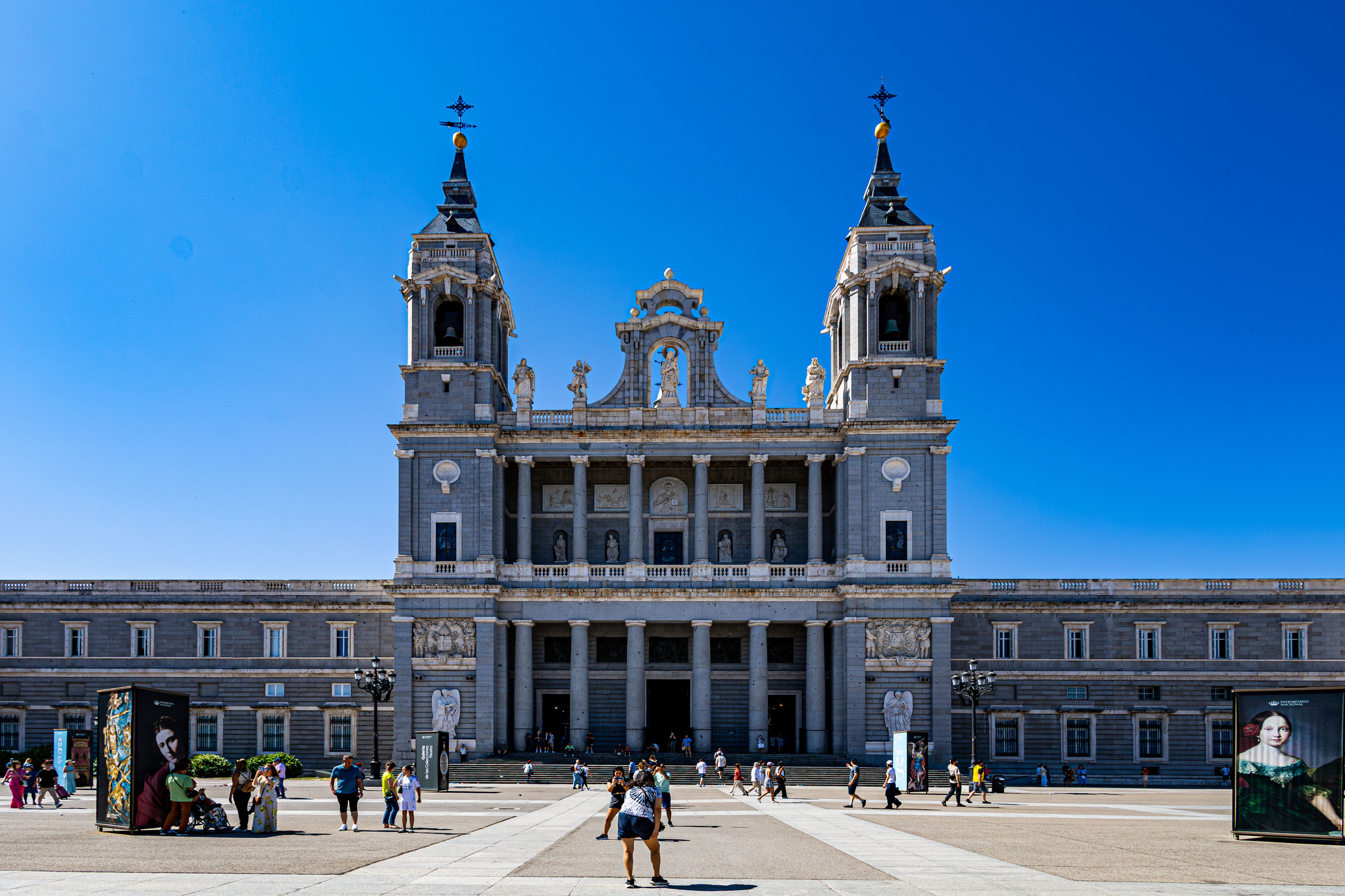 View of Almudena Cathedral with tourists enjoying a sunny day in Madrid Spain.