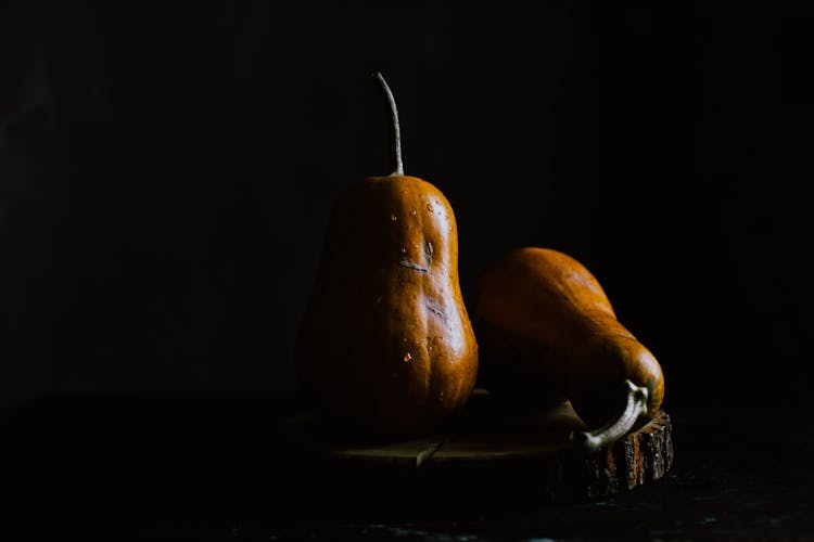 Pear Shaped Pumpkins On Wooden Board In Darkness