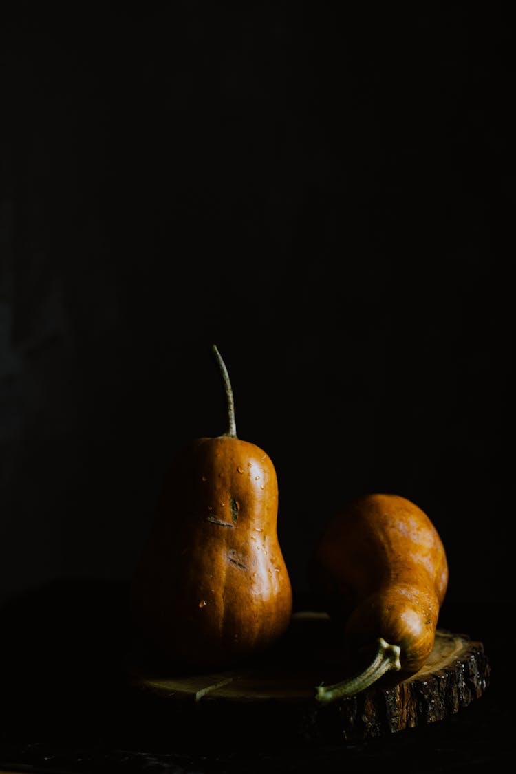 Pear Shaped Pumpkins Served On Wooden Board In Darkness