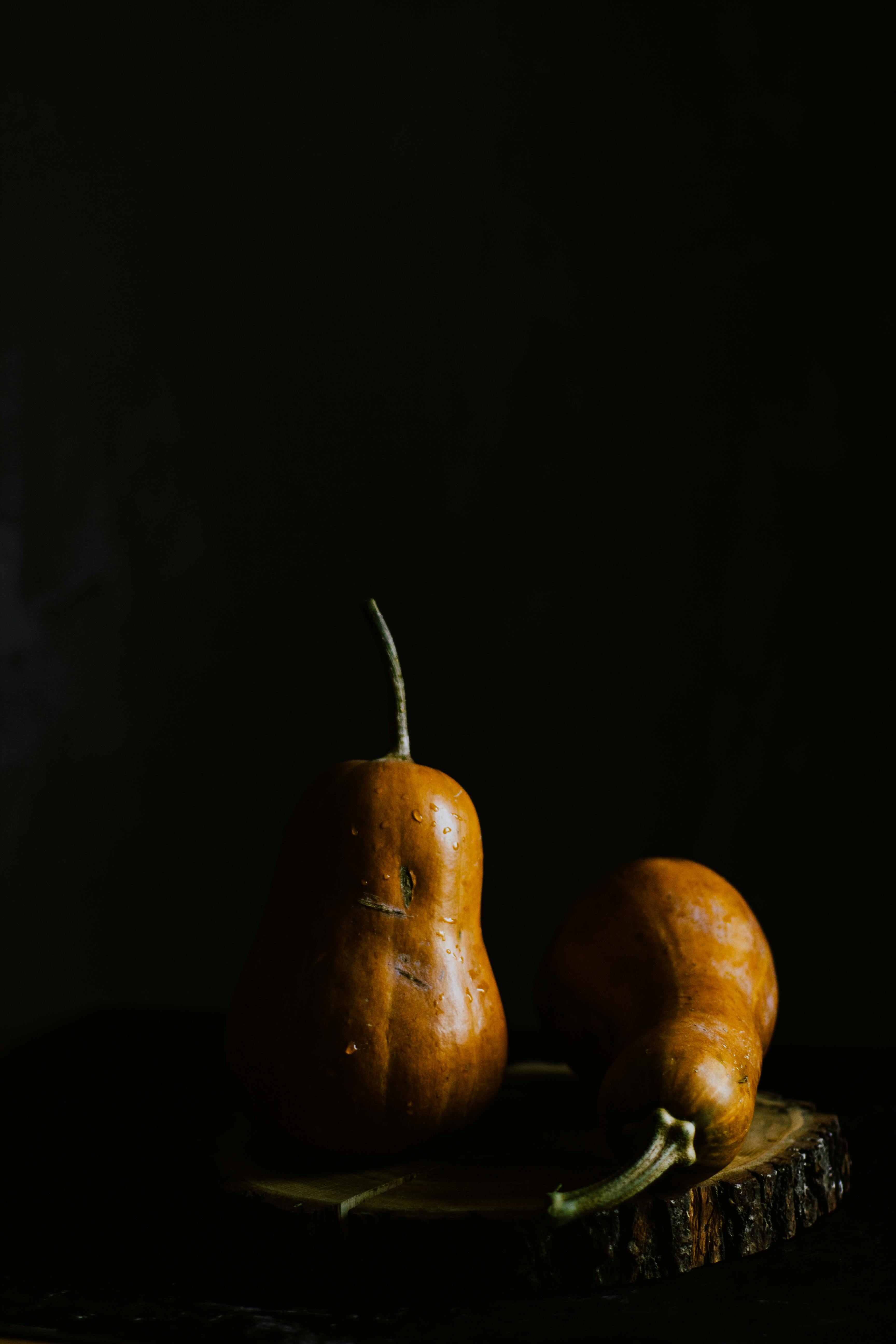 Pear shaped pumpkins served on wooden board in darkness · Free Stock Photo