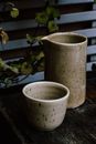 Modern jug and cup made of ceramic placed on wooden table