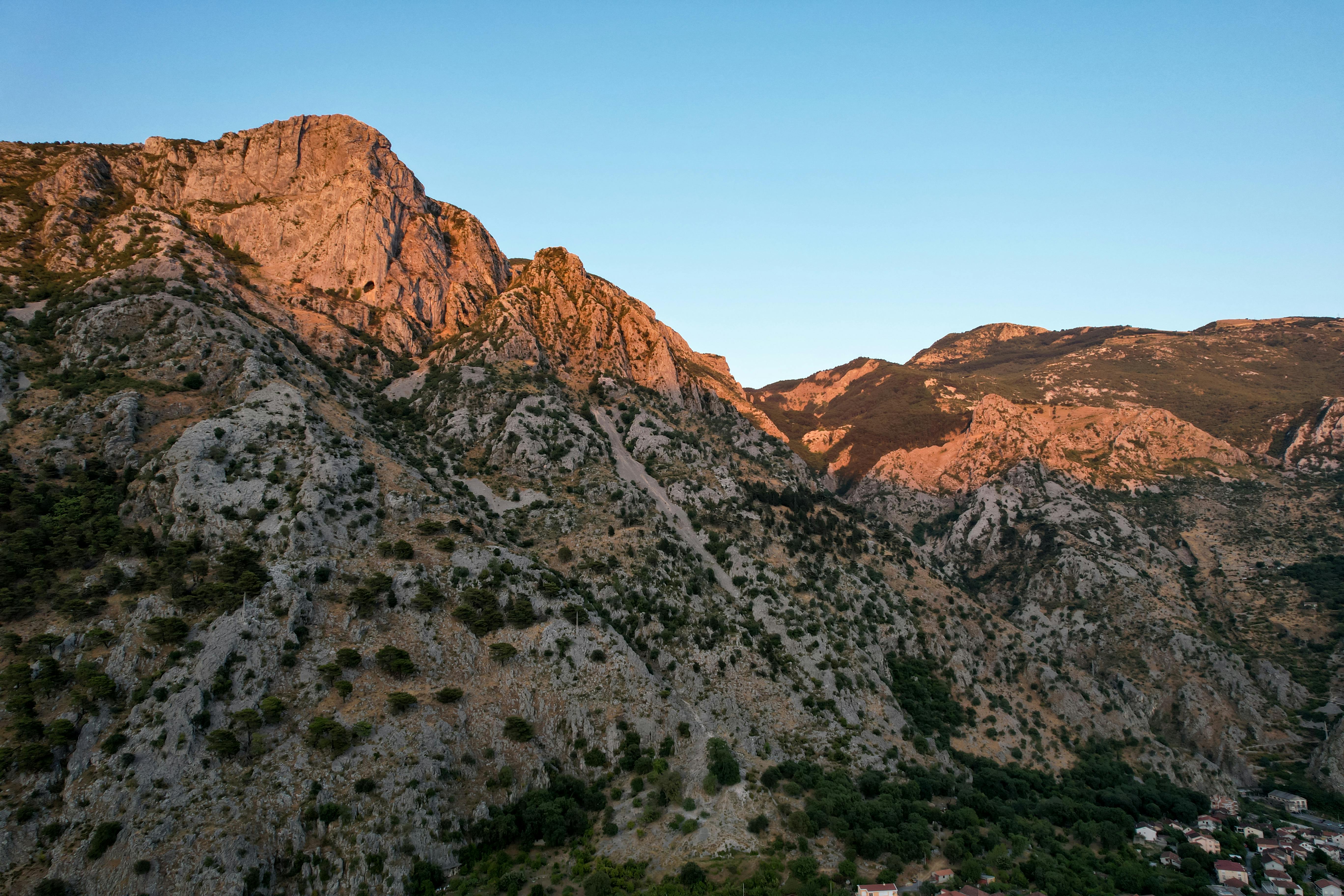 A breathtaking aerial view of a rocky mountain range illuminated by sunset lighting.