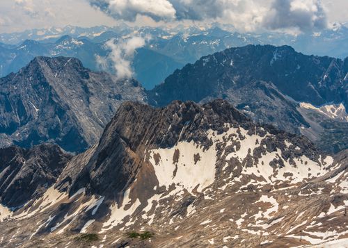 Free Stunning aerial capture of rugged snow-capped mountains under a partly cloudy sky. Stock Photo