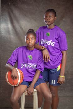 Two young basketball players in purple champion shirts pose with a basketball.