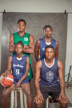 Portrait of a young basketball team posing confidently with jerseys and basketball.