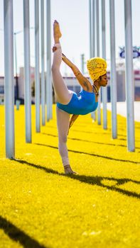A woman performs a yoga pose outdoors in Atlanta, Georgia, surrounded by tall metal posts and vibrant green grass.