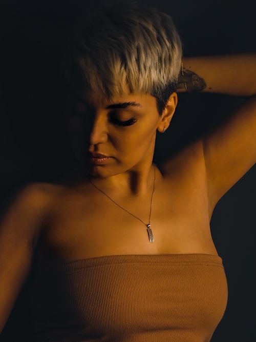 Free Moody portrait of a woman with short hair, adorned with a necklace, captured in low light. Stock Photo