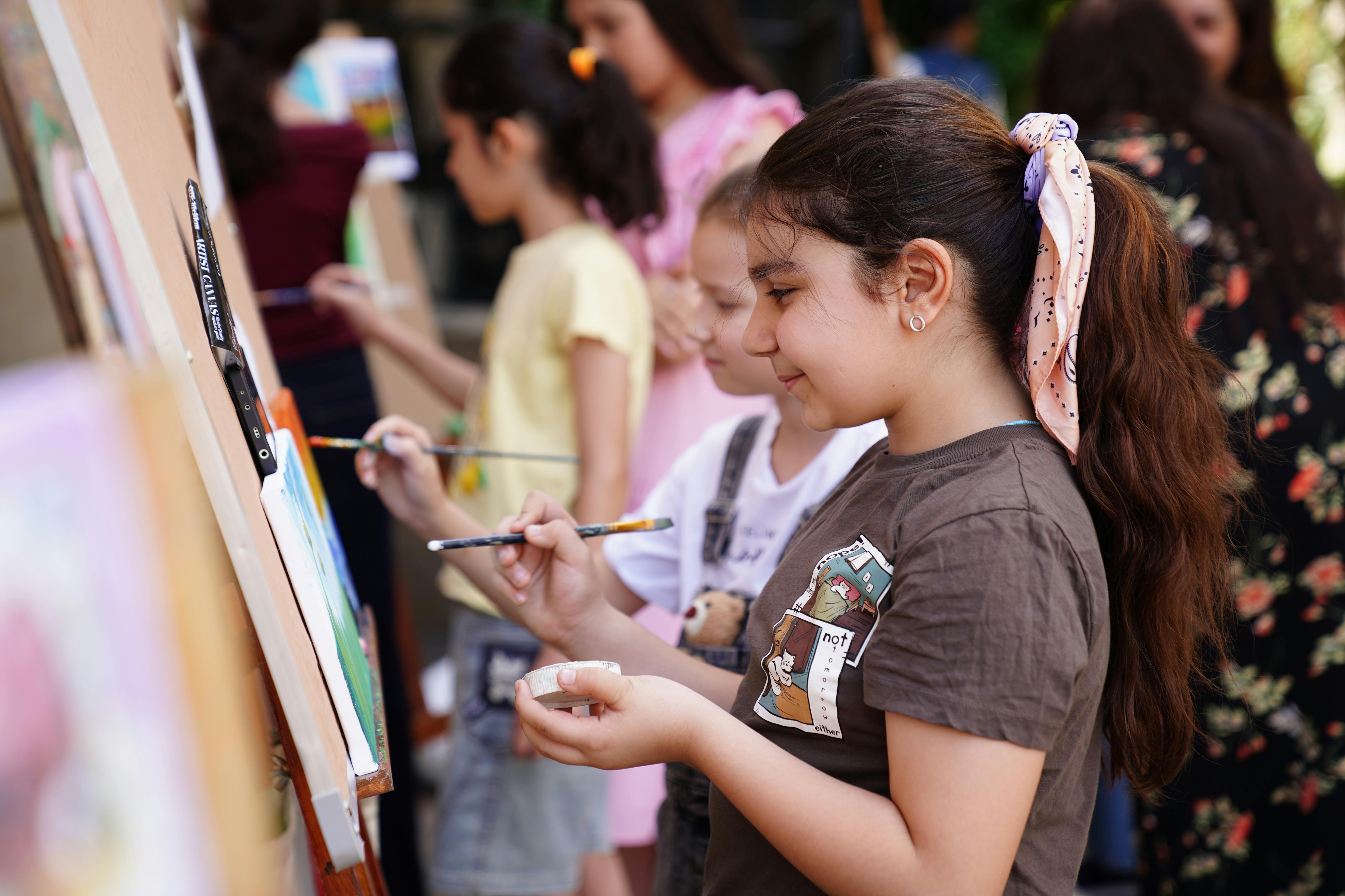Group of children engaged in outdoor painting activities, fostering creativity and teamwork.