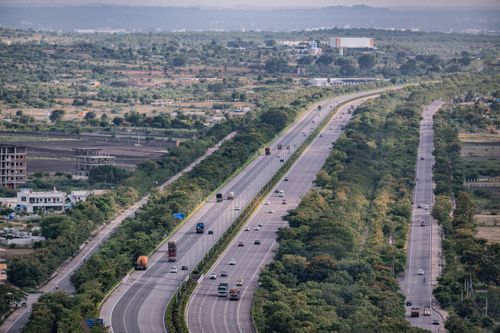 Free Aerial view of a busy highway cutting through lush countryside with cars and trucks traveling below. Stock Photo