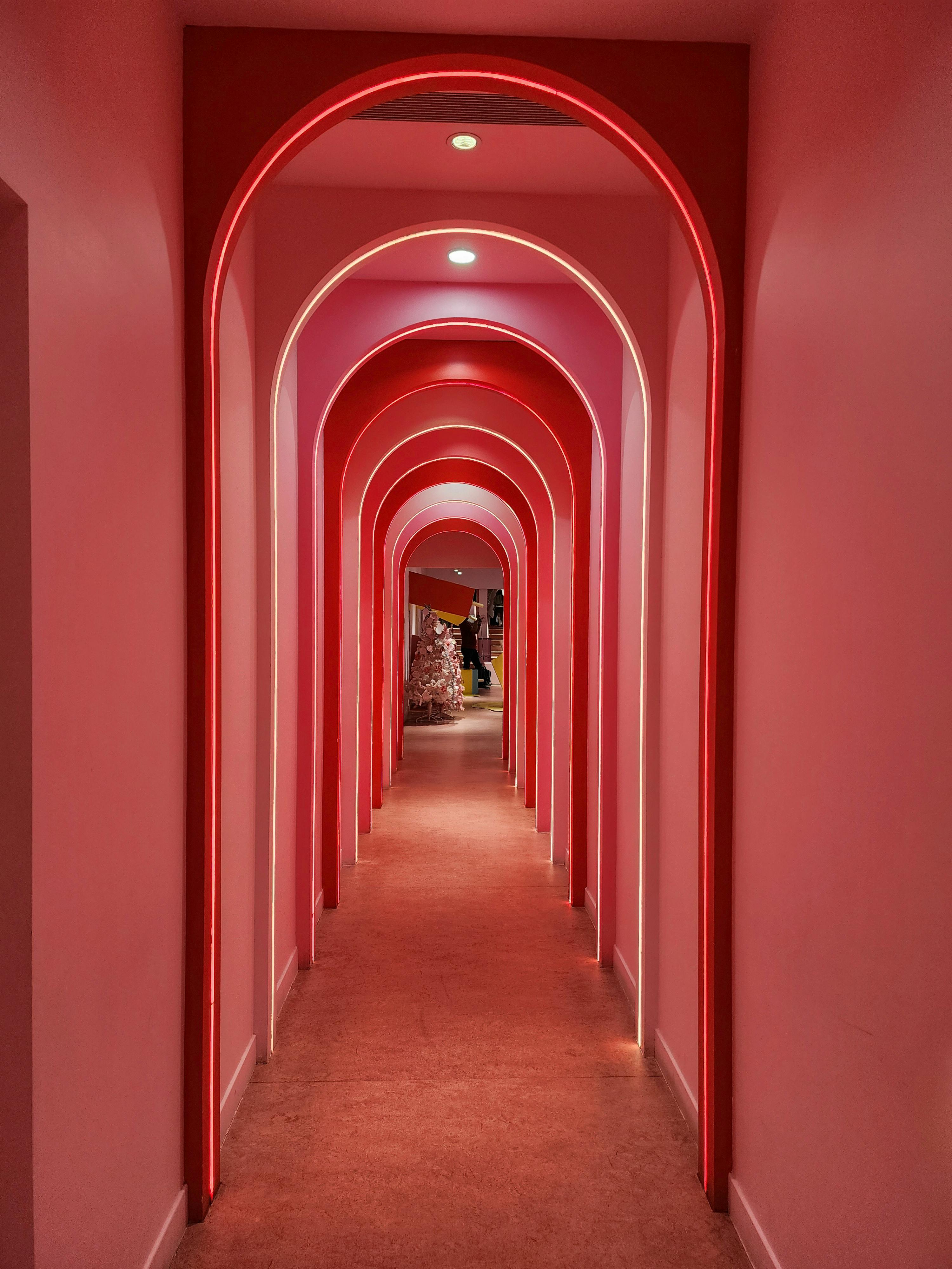 A mesmerizing pink corridor with archways and neon lights creating a surreal and immersive experience.