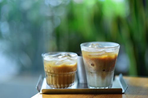 Free Two iced coffee drinks on a tray with a blurred outdoor background for a refreshing look. Stock Photo