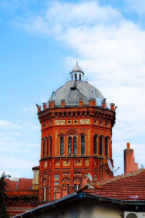 Free An iconic red brick tower stands majestically under a bright blue sky, showcasing architectural elegance. Stock Photo