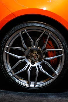Detailed close-up of an orange Corvette's chrome wheel, highlighting automotive craftsmanship.