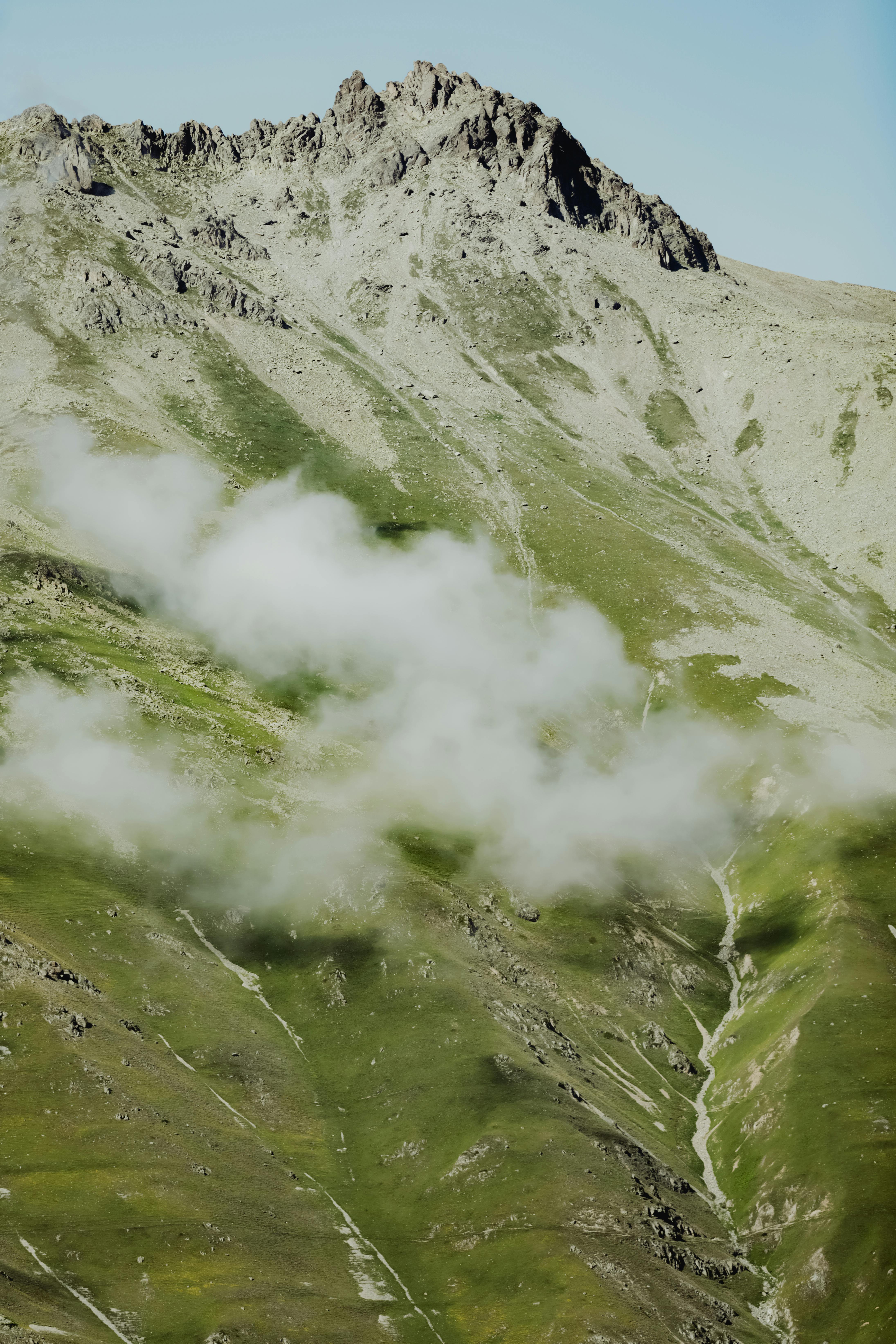 Dramatic mountain peaks with lush greenery and drifting clouds in a serene outdoor setting.