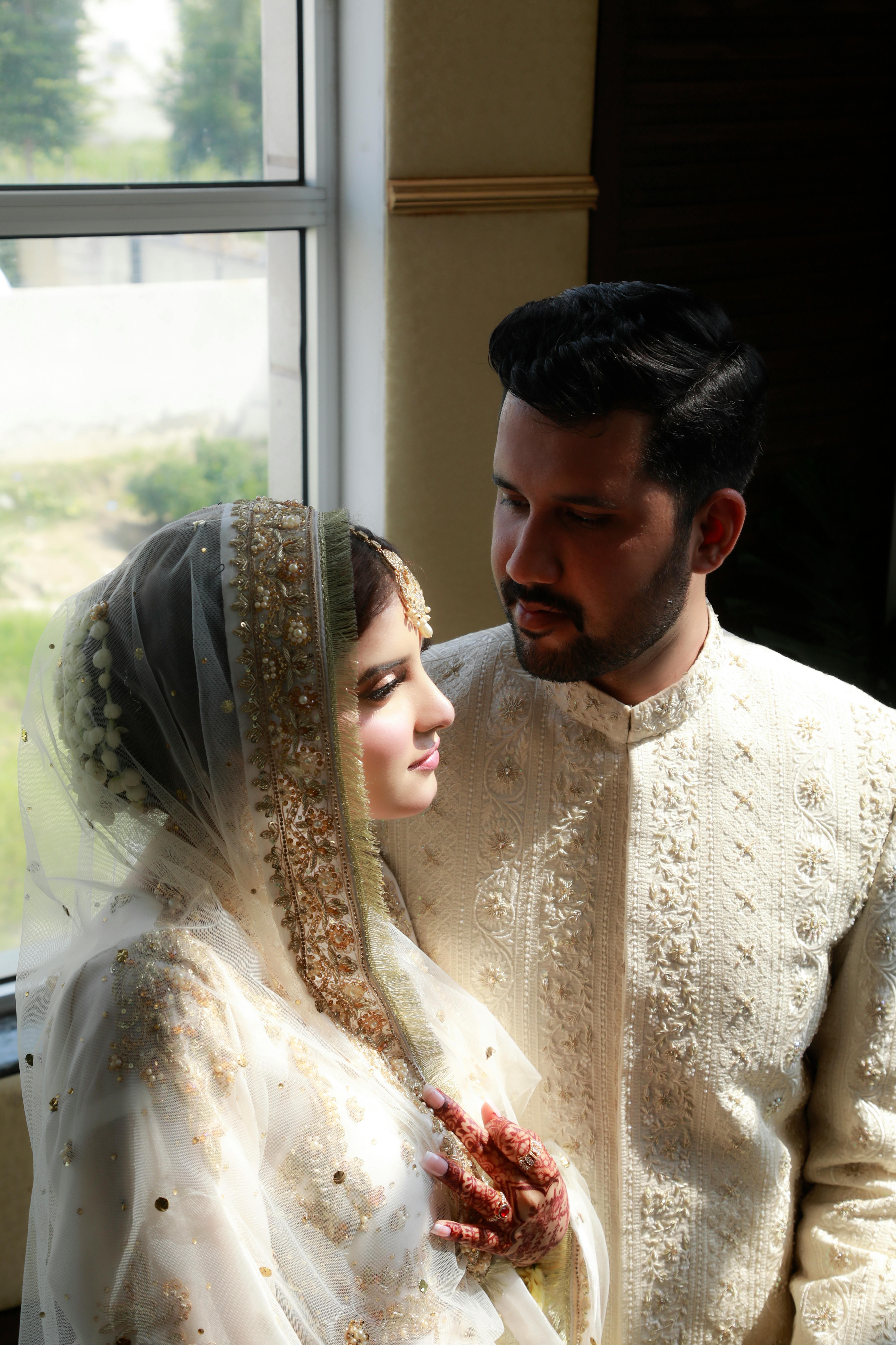 Elegant bridal couple in Lahore adorned in traditional attire with henna designs.