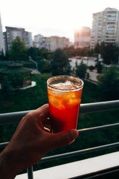 Enjoy a chilled drink on a balcony overlooking a peaceful sunset cityscape.